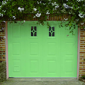 Porte de garage au panneau vert à motif cassettes. Option : 2 hublots rectangulaires au motif losange.